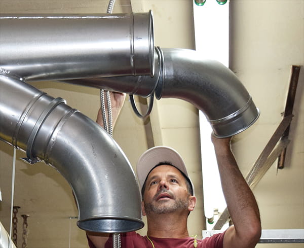 woodworker installing duct in shop